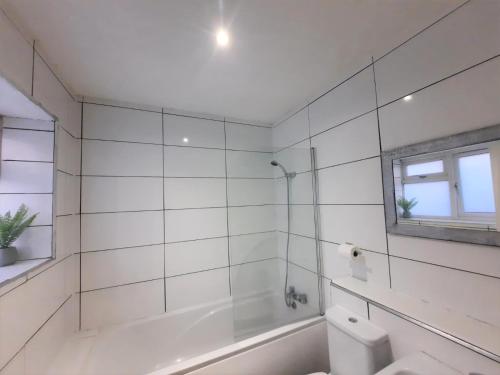 a white bathroom with a tub and a toilet at 3 Bedroom Semi Detached House with parking, WiFi in Colchester