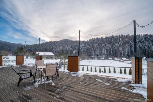 a deck with a table and chairs on a snow covered slope at Rita Art Chalet Voronet in Voroneţ