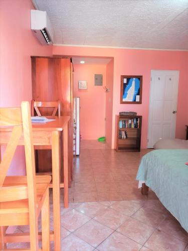 a bedroom with pink walls and a bed and a desk at Beach Side Condos Caye Caulker by CCVH in Caye Caulker