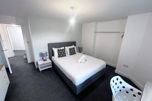a bedroom with a white bed and a chair at Lovely 2-BR Flat near Salford Royal in Manchester
