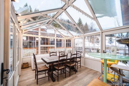 a conservatory with a table and chairs and windows at Rita Art Chalet Voronet in Voroneţ