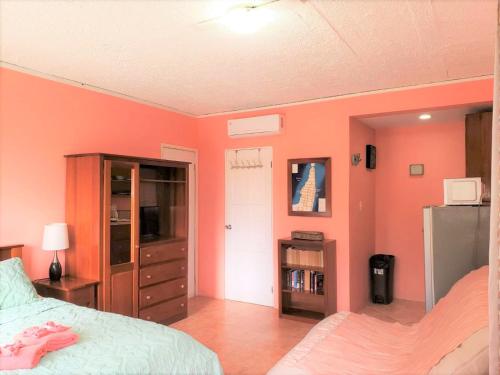 a bedroom with orange walls and a bed and a tv at Beach Side Condos Caye Caulker by CCVH in Caye Caulker
