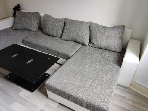 - un canapé gris dans le salon avec une table dans l'établissement Spacieux appartement proche centre - ancien NY, à Mulhouse