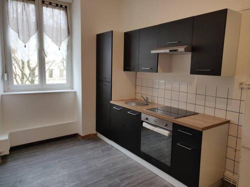 une petite cuisine avec des armoires noires et une fenêtre dans l'établissement Spacieux appartement proche centre - ancien NY, à Mulhouse
