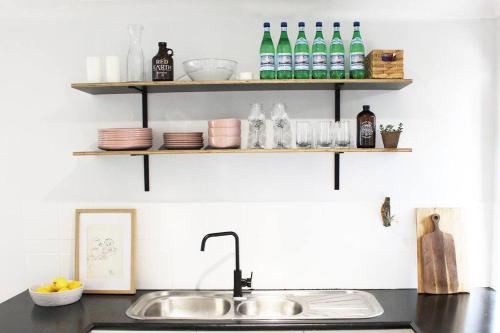 a kitchen counter with a sink and bottles on shelves at Beach Side Villa Walk to Shops-Pub-Beach in Byron Bay