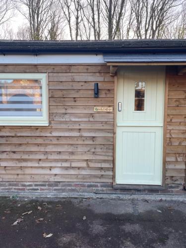 a wooden house with a door and a window at Beech Cottage in Bodiam