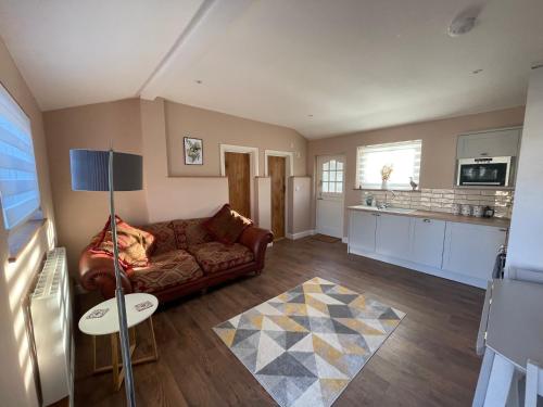 a living room with a couch and a kitchen at Beech Cottage in Bodiam
