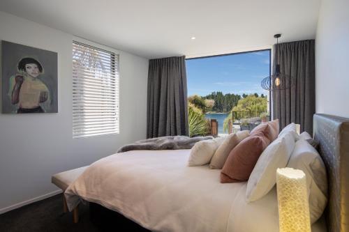 um quarto com uma cama grande e uma janela grande em The Ivy Box Apartment em Queenstown