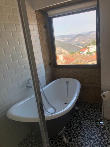 a bath tub in a bathroom with a window at Castas do Douro in Tabuaço