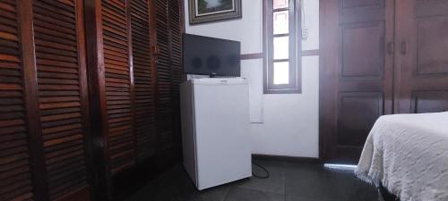 een witte koelkast in een kamer met een bed bij Encantos do mar in Arraial do Cabo
