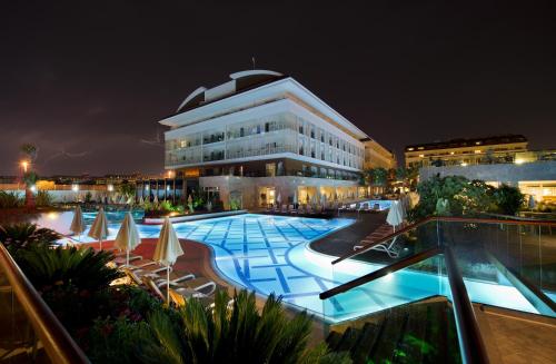 a large building with a swimming pool at night at Sentido Trendy Verbena Beach Hotel in Side