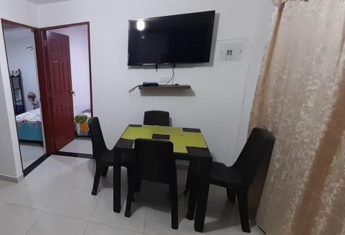 a dining room table with black chairs and a television at J79 Apartamentos Vacacionales in Ibagué