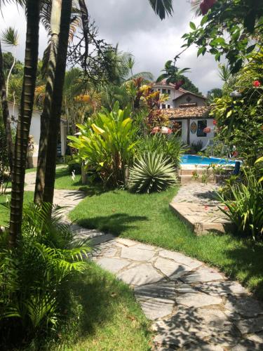 a walkway leading to a yard with a swimming pool at Pousada Casa Pindorama in Santa Cruz Cabrália