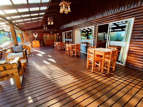 un restaurante con suelo de madera, mesas y sillas en La Casona Caburgua en Pucón