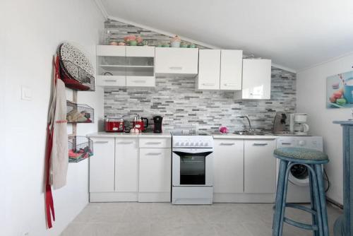 a kitchen with white cabinets and a brick wall at MAISON CHATEAU D'OLERON in Le Château-dʼOléron