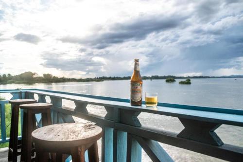 Ban Donsôm Tai的住宿－DON DET Souksan Sunset Guesthouse and The Xisland Riverview Studio，一瓶啤酒坐在水边的桌子上