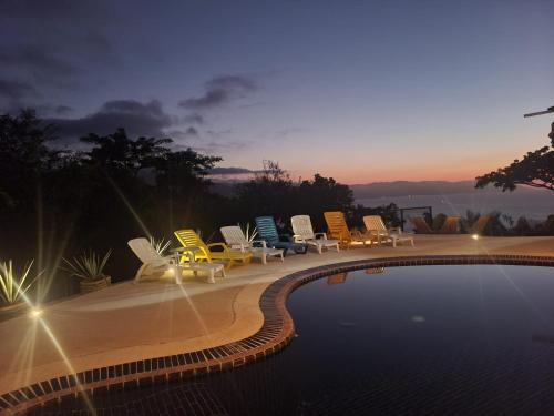 a group of chairs sitting around a swimming pool at Private villa, pool with ocean view and sounds in Puerto Vallarta