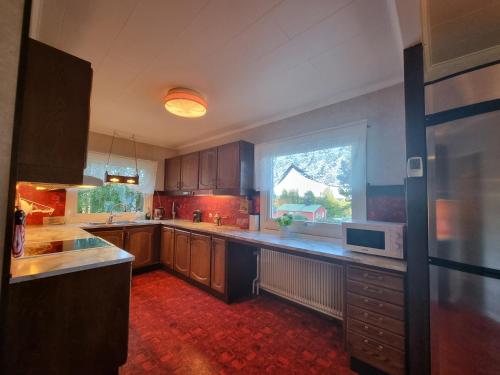 una cucina con armadi in legno e una grande finestra di Cozy house in heart of Swedish Lapland a Vuollerim