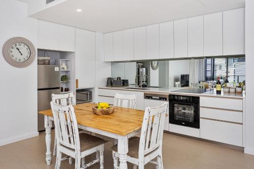 a kitchen with a wooden table and white cabinets at Coastal Souls North Kirra Beach in Gold Coast