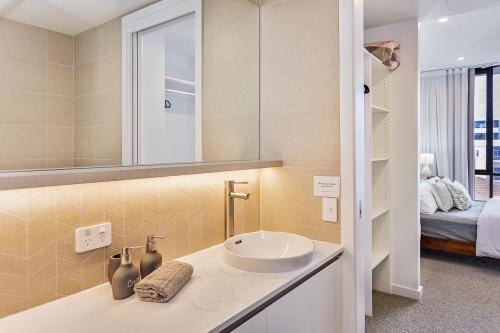a bathroom with a sink and a mirror and a bed at Coastal Souls North Kirra Beach in Gold Coast