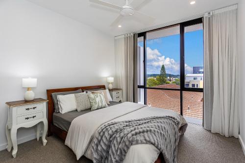a white bedroom with a bed and a large window at Coastal Souls North Kirra Beach in Gold Coast