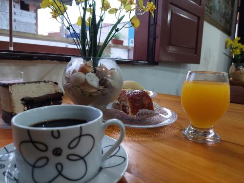 a table with a cup of coffee and a glass of orange juice at Encantos do mar in Arraial do Cabo