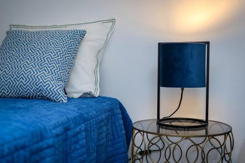 a blue bed with a pillow and a table with a lamp at Casa do Arco in Ponta Delgada