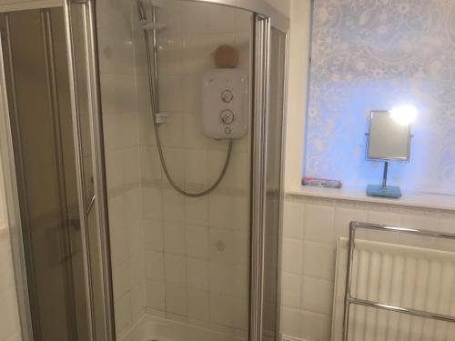 a shower with a glass door in a bathroom at The Kennels- Speyside Self-catering cottage in Aberlour