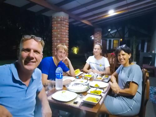 a group of people sitting around a table eating food at Green Cottage in Anuradhapura