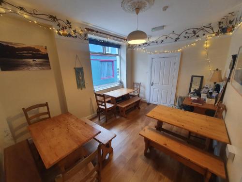 a living room with wooden tables and a dining table at The Grapevine Hostel in Dingle
