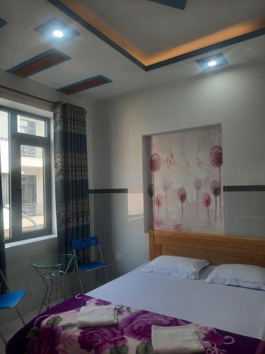 1 dormitorio con 1 cama y una pintura de flores en la pared en Nhà Nghỉ An Toàn en Vung Tau