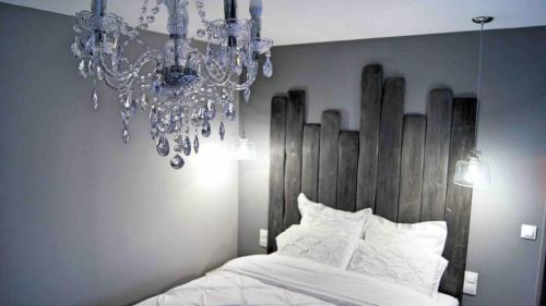 um quarto com uma cama com um lustre por cima em Les Béthunoises Centre Grand-Place - Spa et Sauna em Béthune