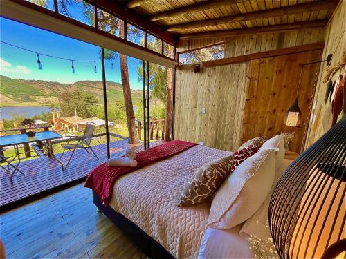 een slaapkamer met een bed en een balkon met een tafel bij Alma de Campo Glamping - Laguna de Suesca in Suesca