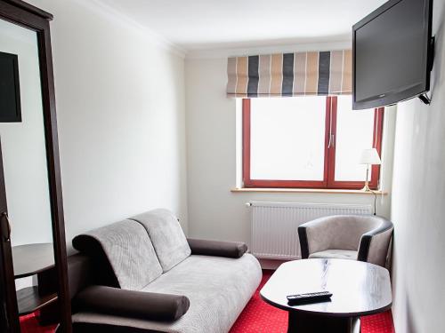 a living room with a couch and two chairs and a tv at Dworek Szwajcaria in Zwardoń