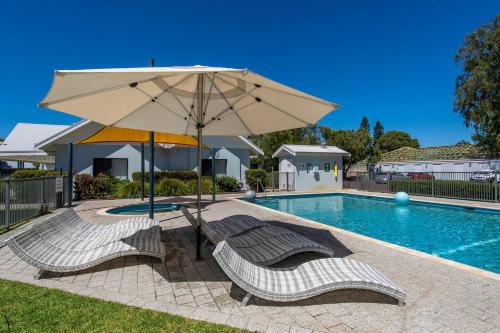 a pool with two chairs and an umbrella at Seventy at Cape View Resort in Busselton