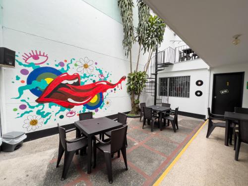 een restaurant met tafels en een muurschildering bij Rock Hostel Medellin in Medellín