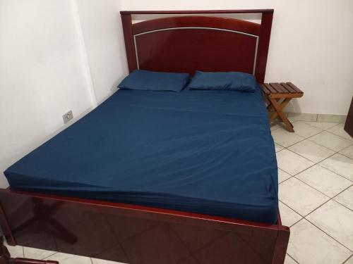 1 cama con sábanas azules y cabecero de madera en Linda vista para a praia em Mongaguá, en Mongaguá