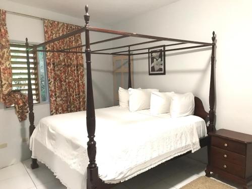 a bedroom with a black canopy bed with white sheets at Chateau Margarita JA in Montego Bay