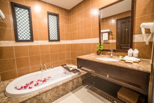 a bathroom with a tub and a sink and a mirror at Pandanus Resort in Mui Ne