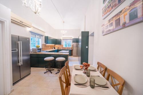 Art Apartment In Mamila - Villa Rehavia في القدس: مطبخ مع طاولة وكراسي وثلاجة