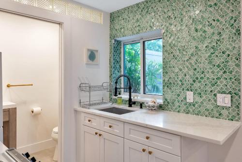 a bathroom with a sink and a window at Art Deco Pool house mile and a half to beach Pets Welcome in Lake Worth
