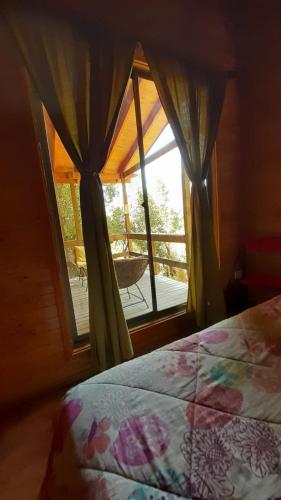 a bedroom with a bed and a window with a patio at Cabañas Lihuén SPA in Parral