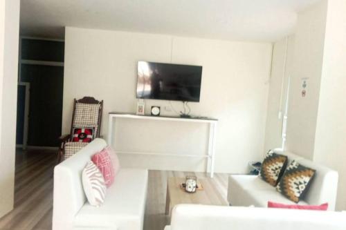 a living room with two white couches and a tv at Na - cha - lae (3) in Chanthaburi