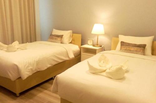 a bedroom with two beds with white sheets and a lamp at Na - cha - lae (3) in Chanthaburi