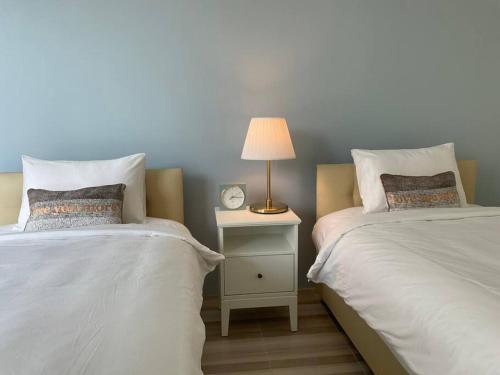 a bedroom with two beds and a lamp on a night stand at Na - cha - lae (3) in Chanthaburi
