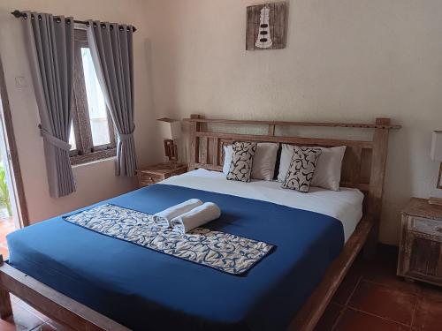 a bedroom with a bed with a blue blanket at Mango 5 Hotel in Amed