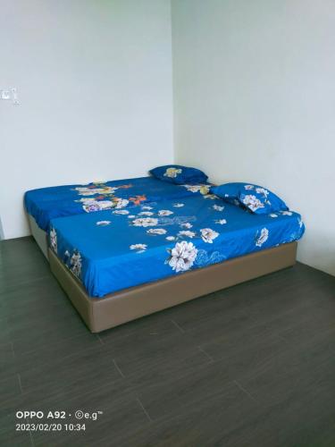 Una cama con un edredón azul con flores. en KERAYONG IMPIAN HOMESTAY, en Kampong Kerayong