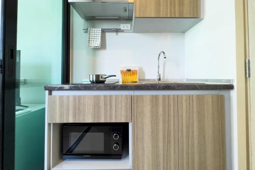 a kitchen with a sink and a microwave at Wellness Stay & Hotel Sukhumvit 107 in Bangna