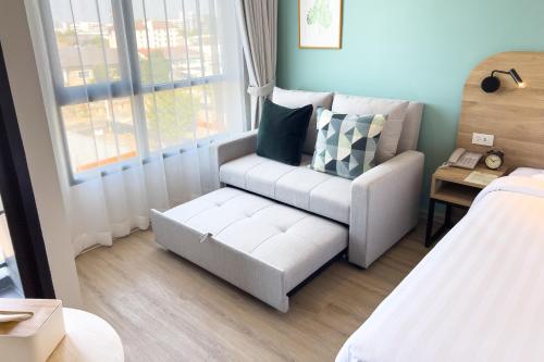 a small room with a couch and a chair at Wellness Stay & Hotel Sukhumvit 107 in Bangna