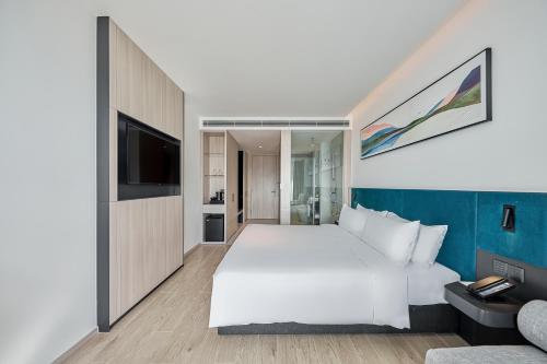 a bedroom with a large white bed and a tv at December Hotel in Nha Trang